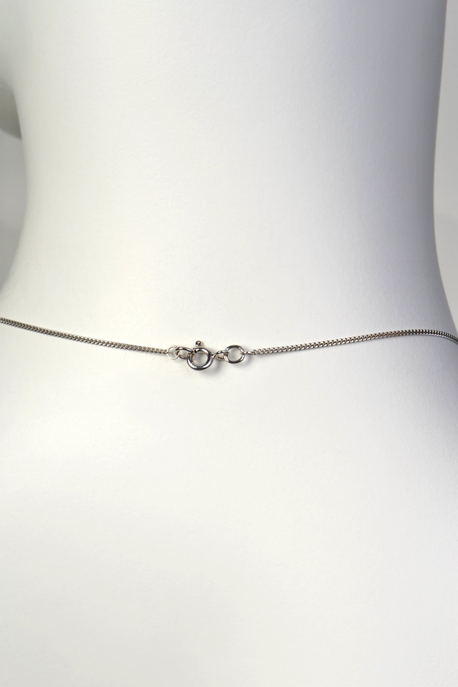 Detailed close-up of a small, discrete 9ct white gold bolt ring clasp on a fine curb chain. Christine Sadler