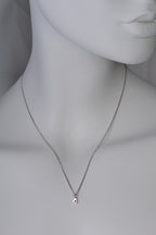 Small polished white gold heart necklace with a ruby displayed on white mannequin to show size and scale when on a 45cm long chain