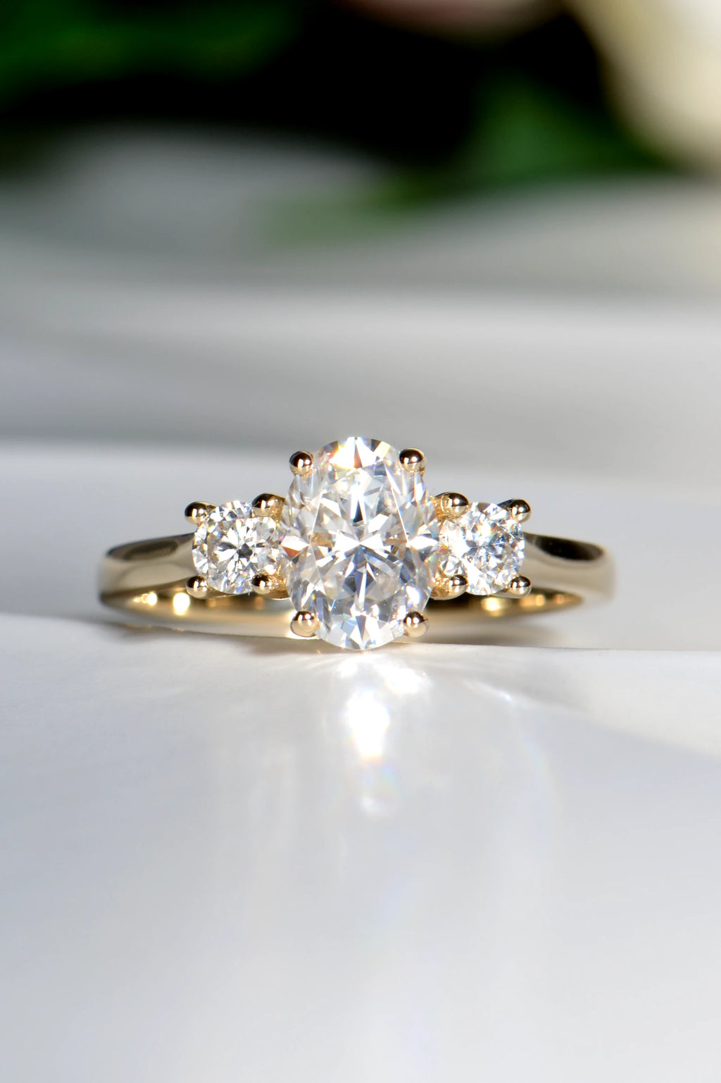 Handcrafted 9ct yellow gold trilogy engagement ring featuring a central oval moissanite stone flanked by two round brilliant cut side stones.