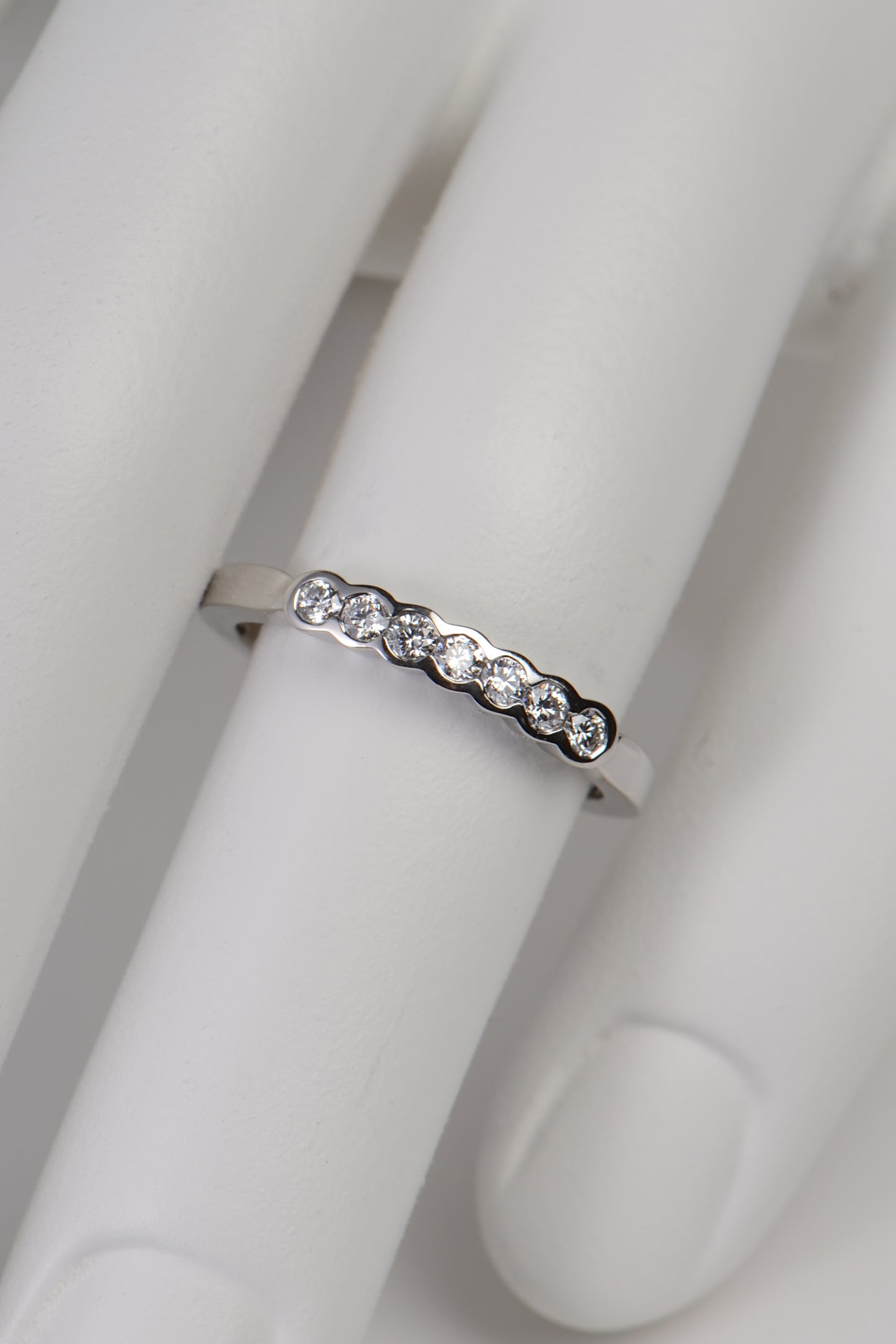 modern narrow diamond set wedding ring in platinum made in the UK set with seven diamonds in secure rubbed over settings