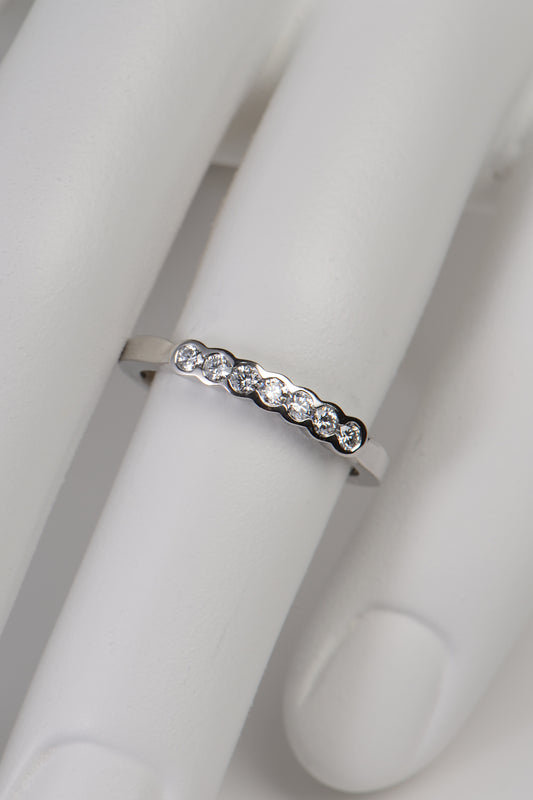 modern narrow diamond set wedding ring in platinum made in the UK set with seven diamonds in secure rubbed over settings