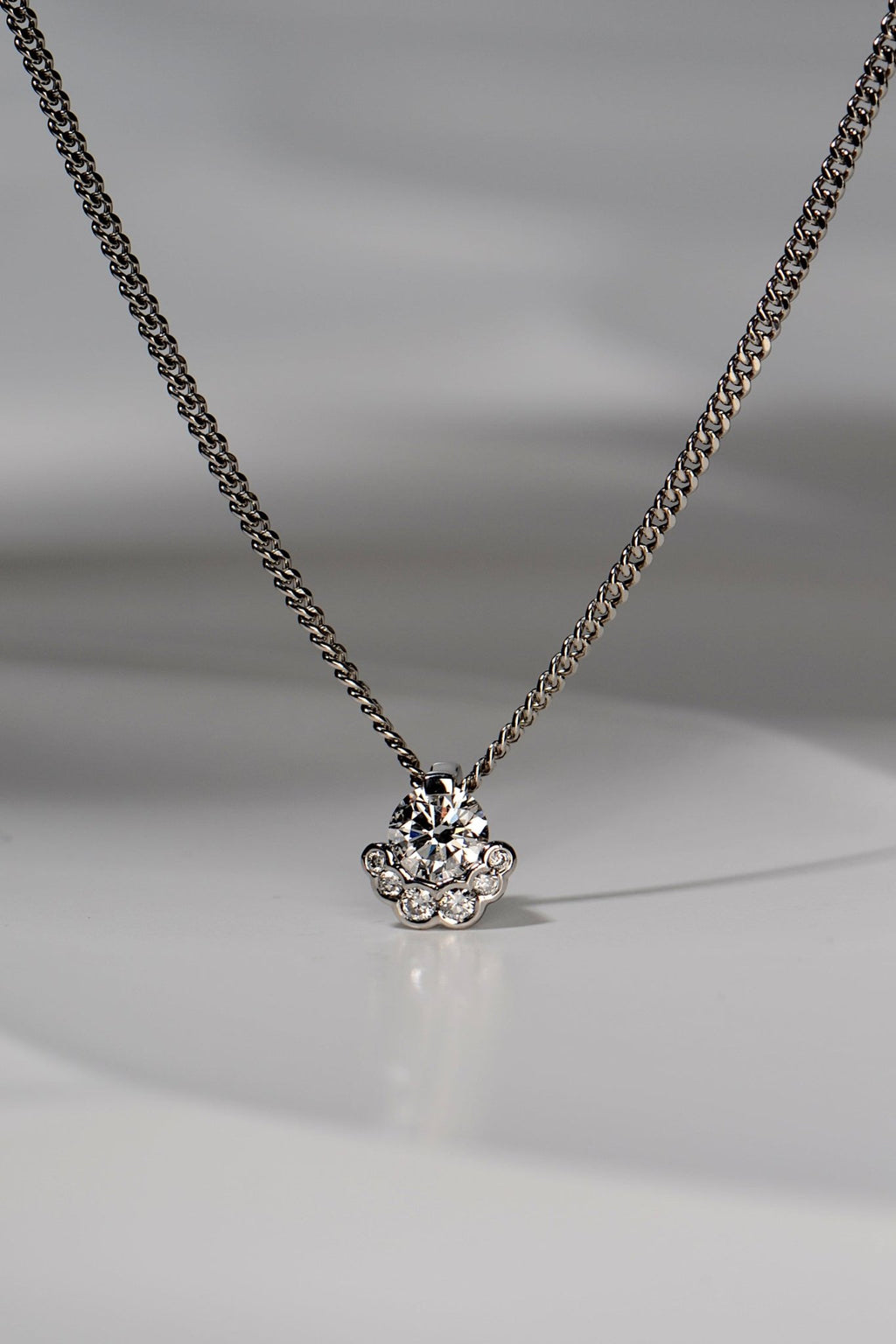 platinum designer lab grown necklace that is special and different set with one larger central stone surrounded on the bottom half by six smaller stones. The design is inspired by the Scottish Fairy Pools on the Isle of Skye exclusively available from Christine Sadler