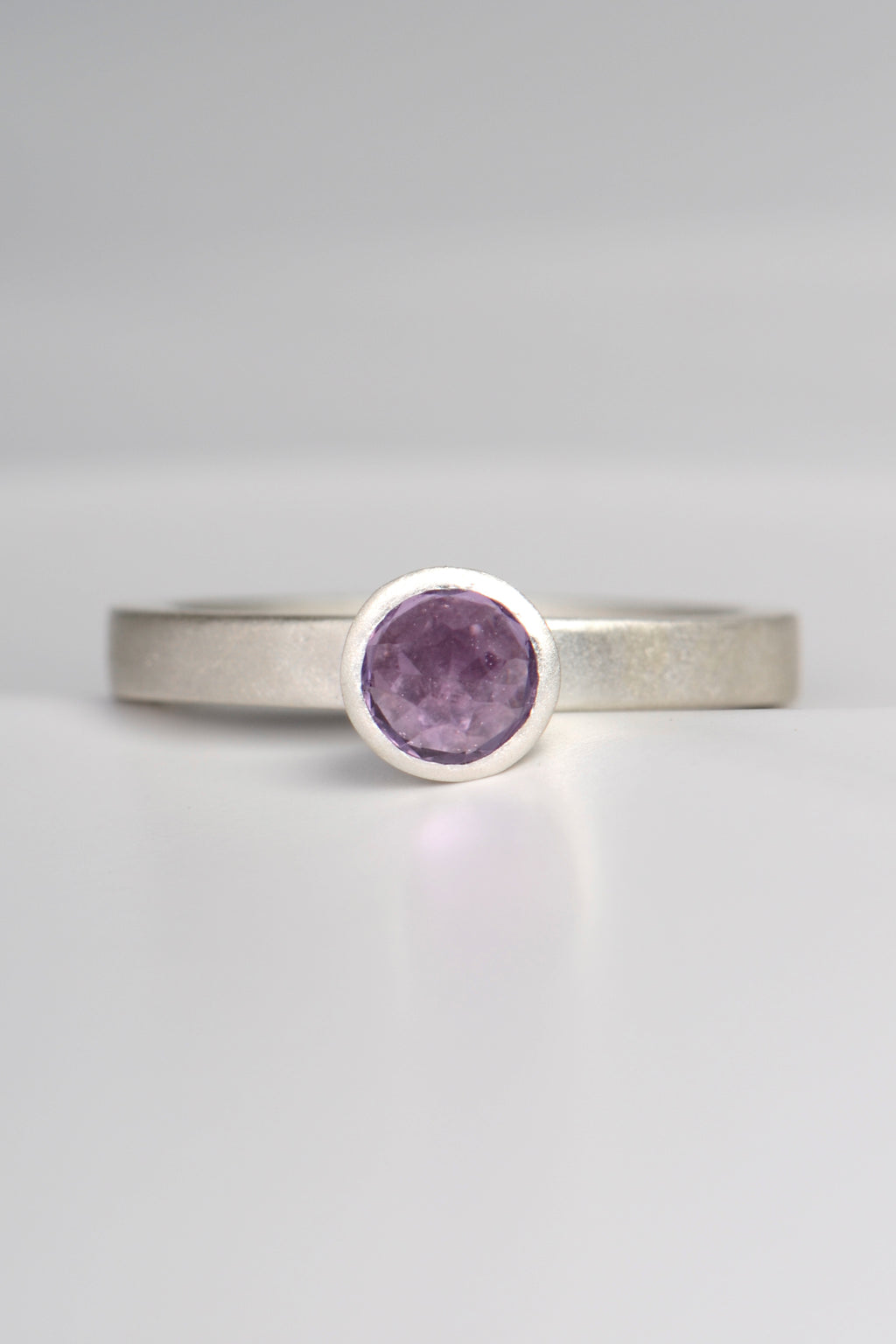contemporary handmade silver designer ring with an amethyst gemstone. This ring is designed to look like a cupcake. It has a narrow band and can be stacked with other rings if desired.