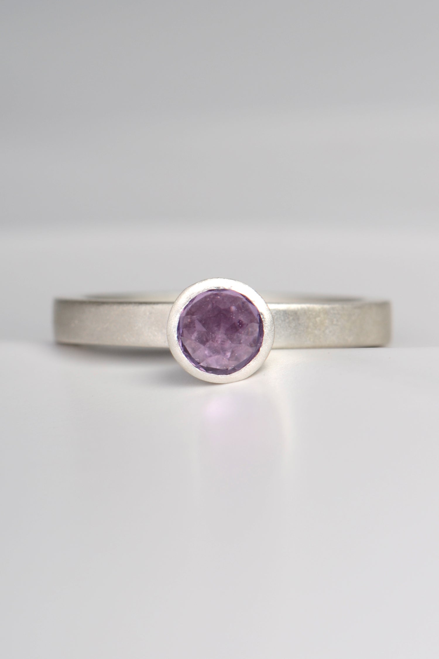contemporary handmade silver designer ring with an amethyst gemstone. This ring is designed to look like a cupcake. It has a narrow band and can be stacked with other rings if desired.