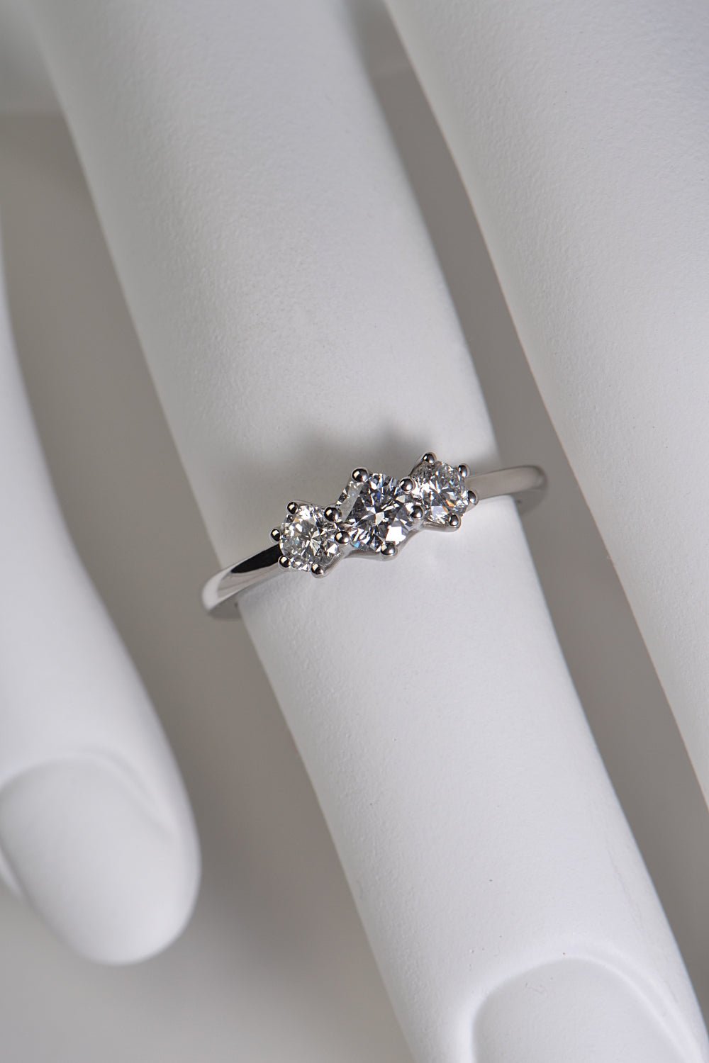 Platinum cathedral three stone diamond engagement ring shown on hand to display scale and height of setting