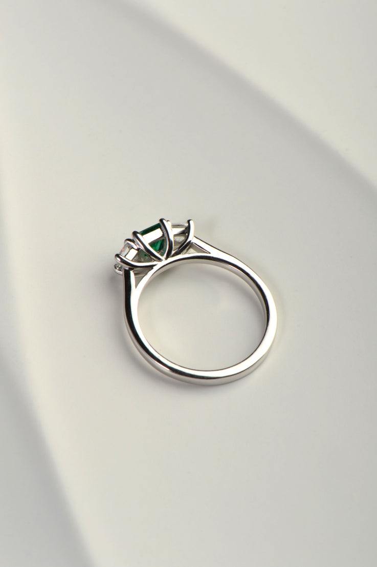 side view of emerald and diamond engagement ring showing the sweeping angles that allows a wedding ring to snuggle fit next to it. Exclusively from UK jewellery designer Christine Sadler