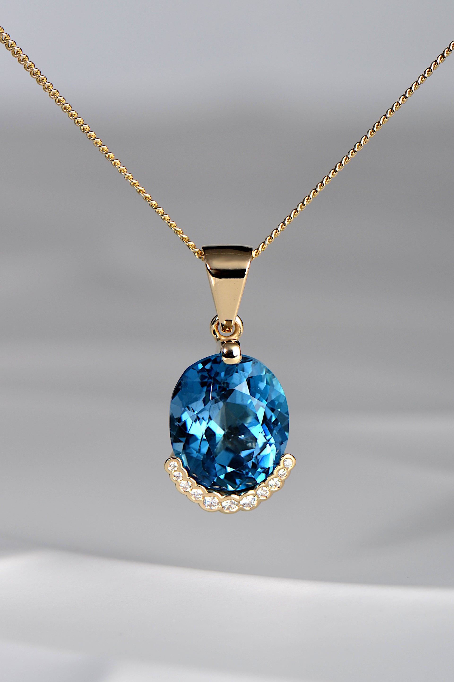 large oval blue topaz necklace with diamonds in yellow gold by scottish jewellery designer Christine Sadler inspired by the Fairy Pools on the Isle of Skye