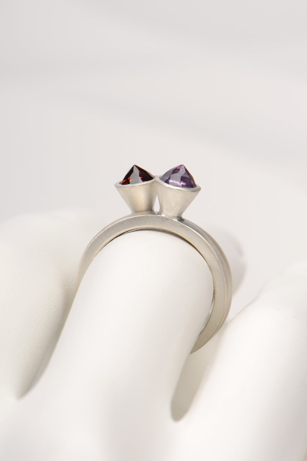 two silver rings stacked together with an amethyst and a garnet gemstone by british jewellery designer Christine Sadler