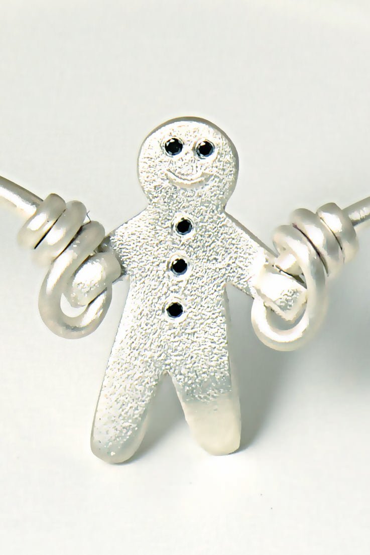 smiling silver gingerbread man with black diamonds that looks like he is skipping with silver wire to form a cute bangle - British jewellery designer Christine Sadler