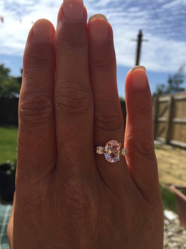 Oval cut morganite with two round diamonds in 18ct white gold ring on hand