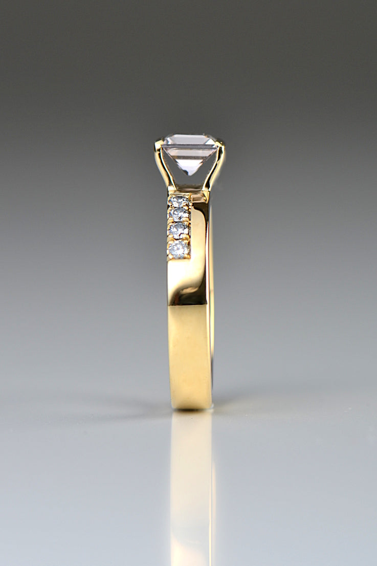 Side view of an 18ct yellow gold gemstone ring set with a square morganite which is held above the band by two sheets of gold that show the full side of the gemstone side on as if it was tension set. 