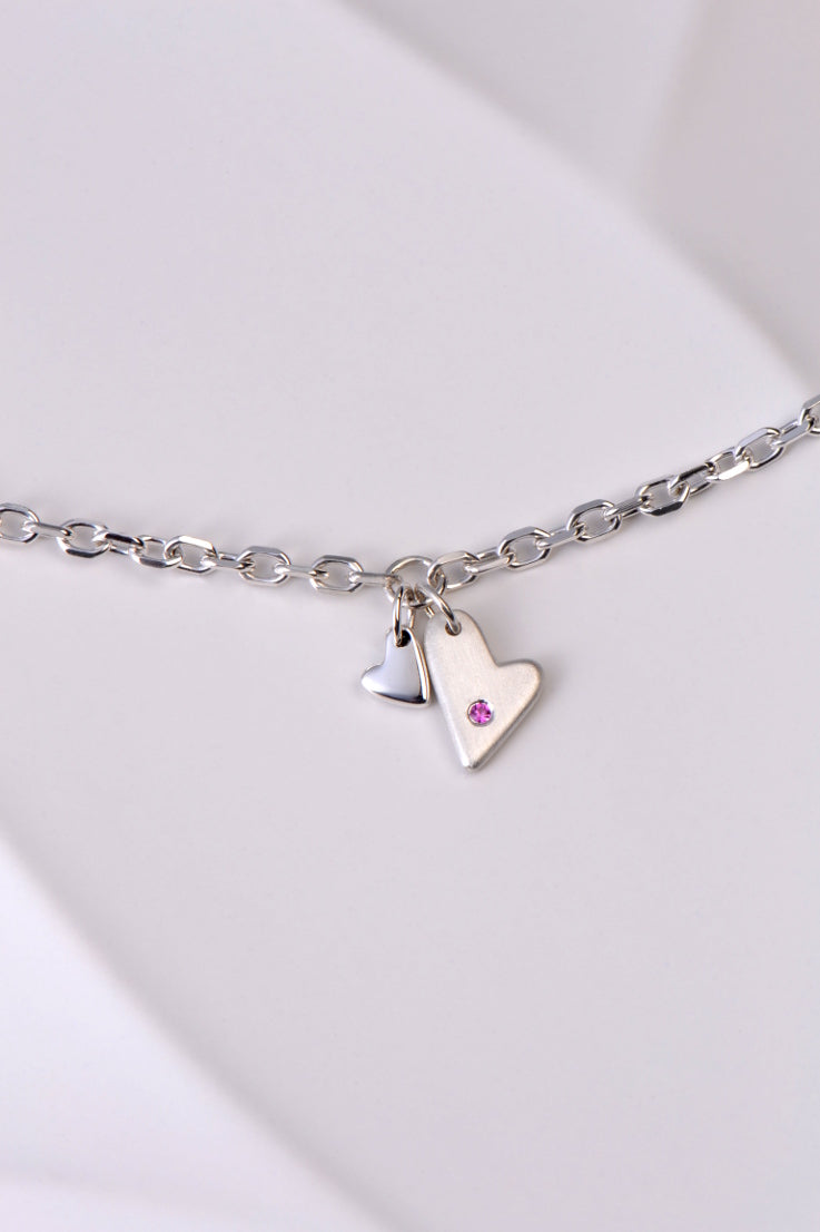 delicate modern silver heart bracelet handmade and set with a pink sapphire