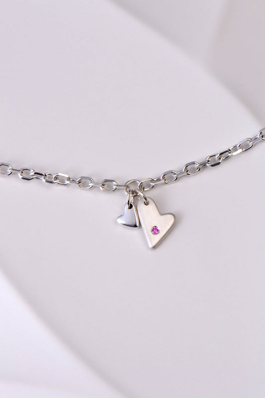 delicate modern silver heart bracelet handmade and set with a pink sapphire