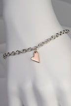 detail of Sterling silver bracelet with two highly polished 9ct rose gold hearts showing the large heart at the front on a white mannequin hand to show size and scale - From The Heart collection