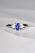 stunning oval cut intense blue tanzanite engagement ring set with two round diamonds, one on either side of the tanzanite. Each stone is held by four claws and it is made in platinum. 