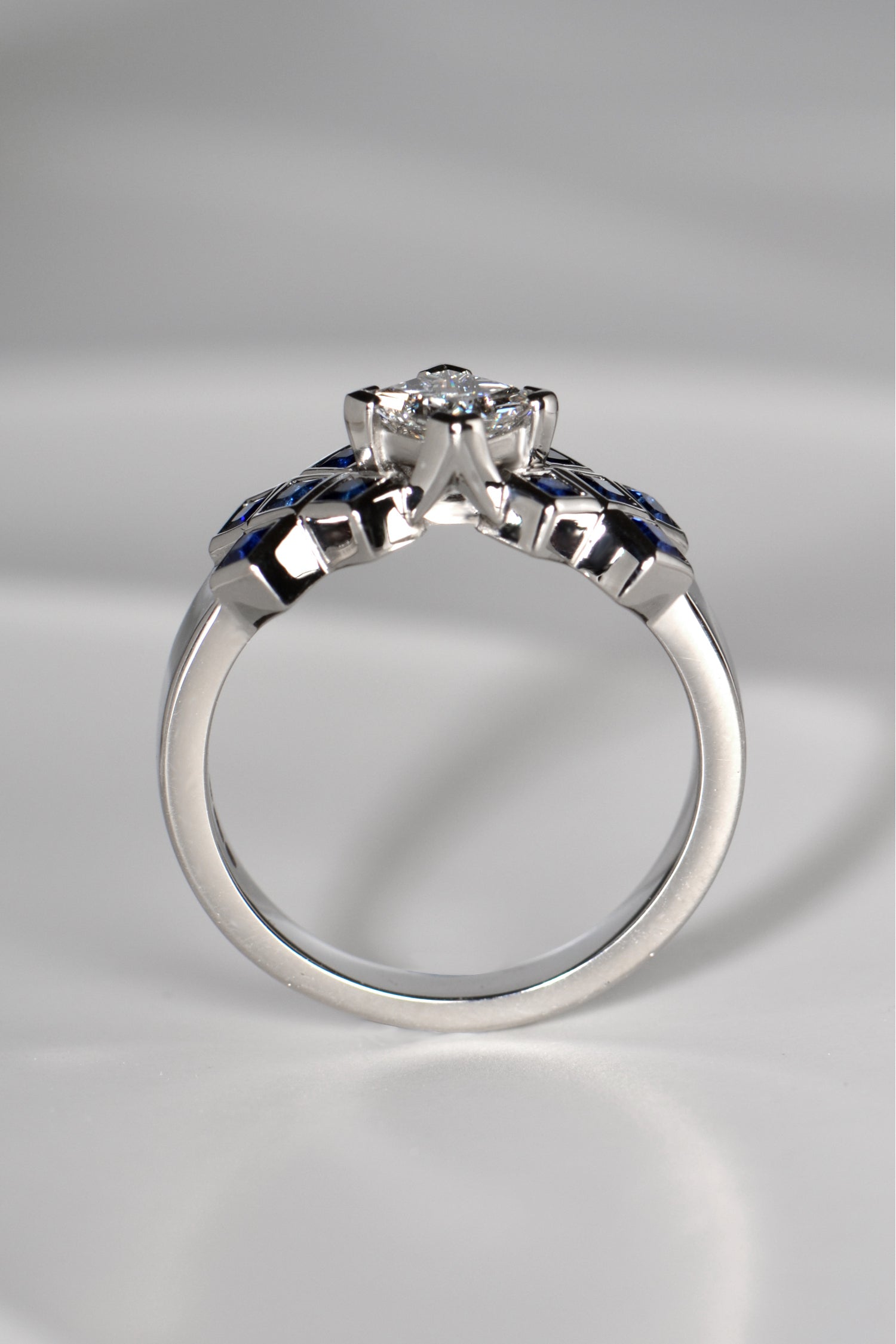 The diamond in the tartan ring is set higher than the sapphires so it looks like a rock rising out of a sapphire sea.