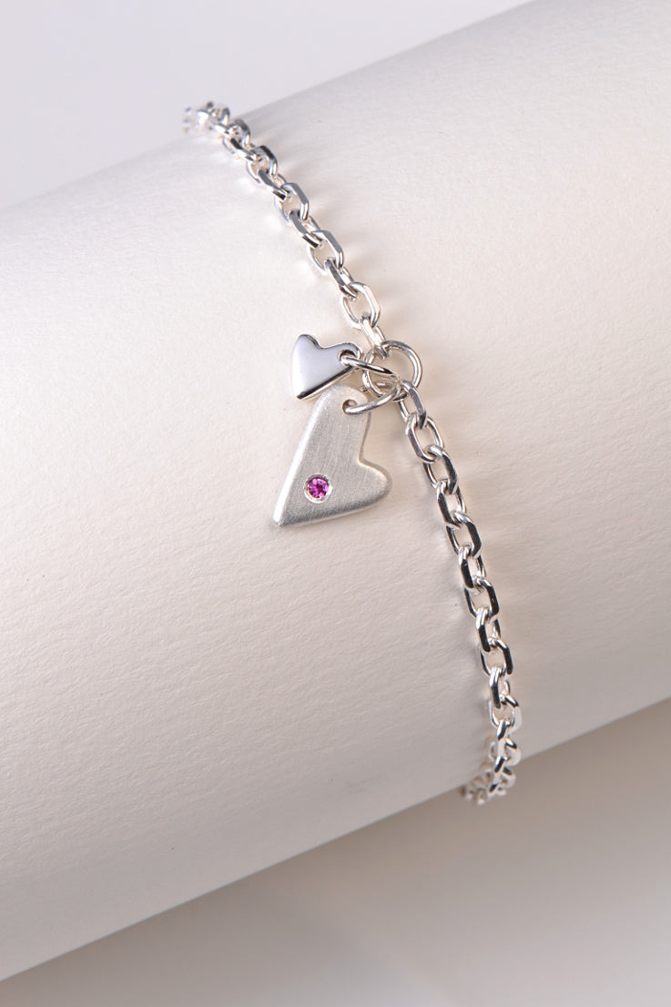 handmade silver bracelet for a woman or a girl with two hearts, one of which is set with a pink sapphire