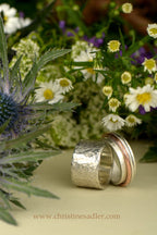 Two handmade textured wedding rings with woodland flowers and Scottish thistle